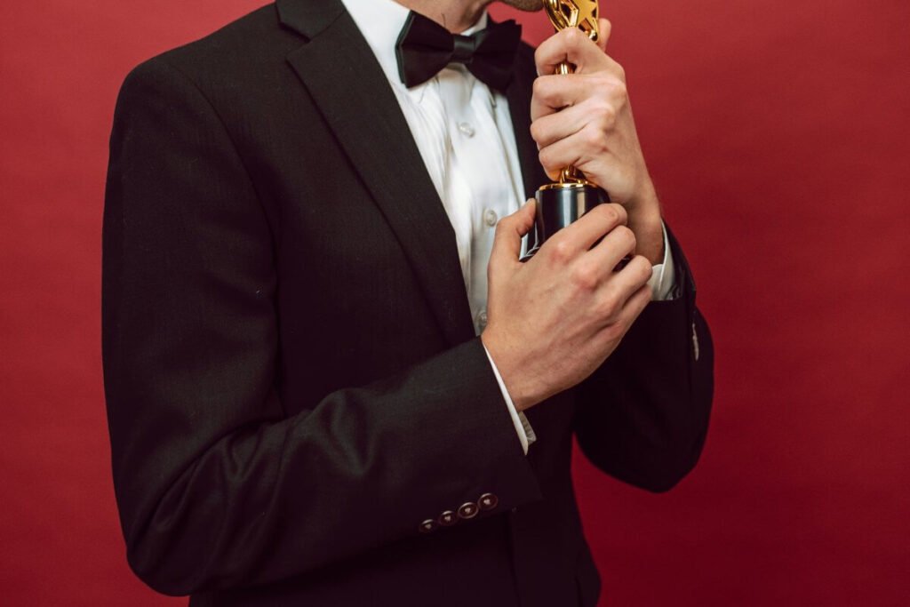 muškarac u odelu drži statuu koja liči na Oskara