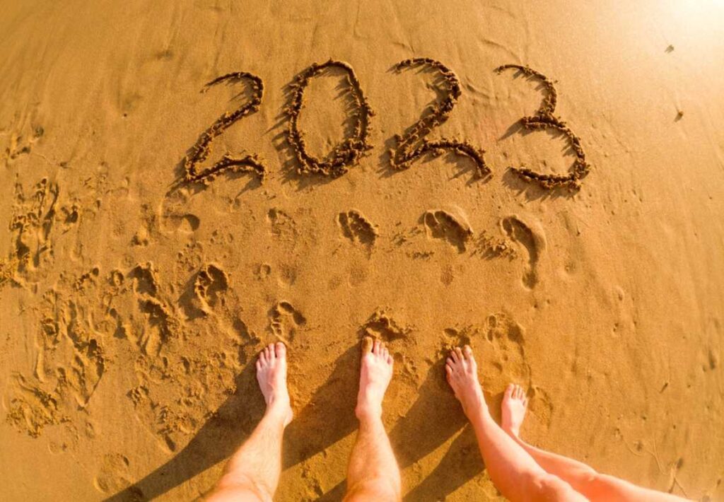 Pesak u kome je ispisano 2023., pored se vide muška i ženska stopala. očigledeno par koji je ispisao brojeve stoji i posmatra.