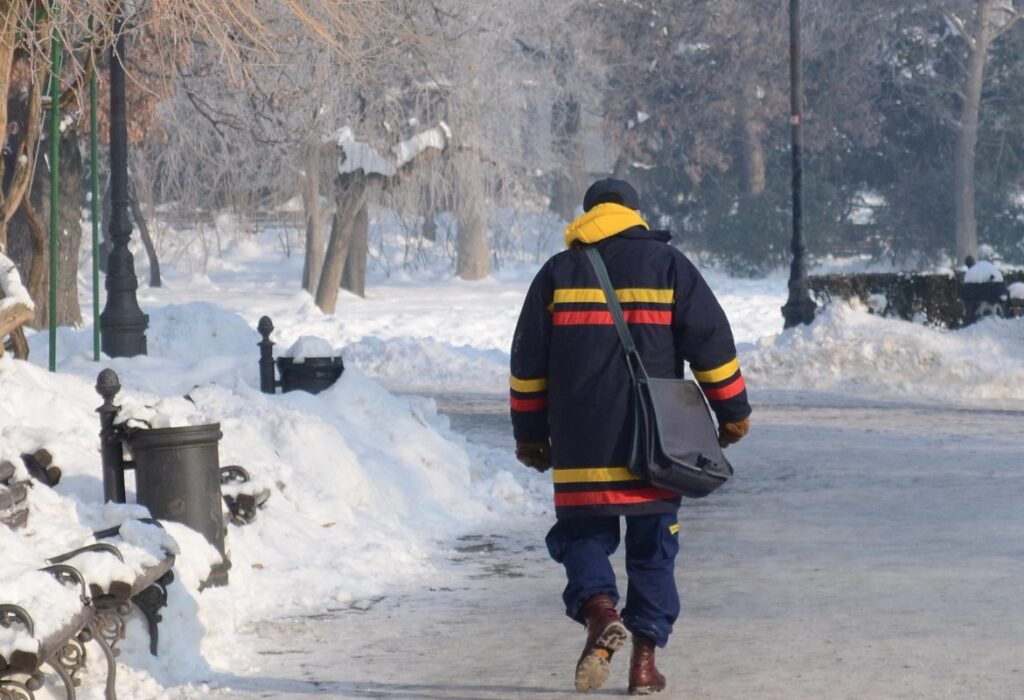 Poštar, nosi torbu sa pošiljkama , po snegu