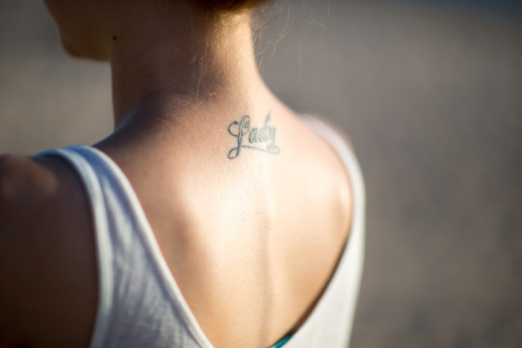 Tetovaža na vratu, ispod podignute kose, natpis Lady