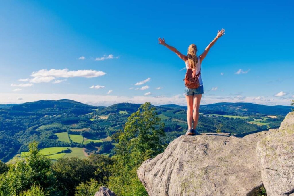Srećna žena raširenih ruku na vrhu planine.