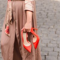 zena nosi crvene cipele u ruci