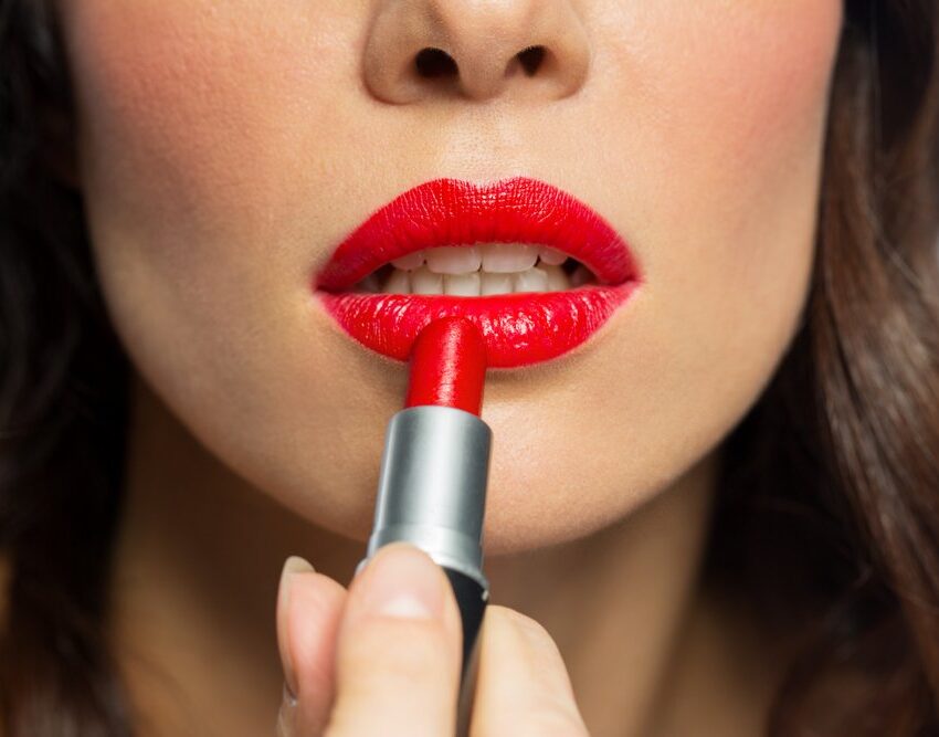 devojka stavlja crveni karmin na usne