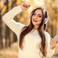 devojka sa slušalicama šeta po šumi