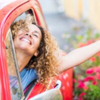 nasmejana devojka u crvenim kolima