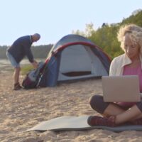 zena radi na laptopu na plazi