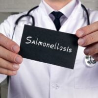 Doktor u ruci drži crnu karticu na kojoj piše Salmonellosis.