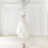 Predivna venčanica okačena o kristalni luster, a na podu su svečane cipele.