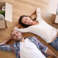 Srećni par koji leži na podu pored njih su kutije za zapakovanim raznim stvarima.