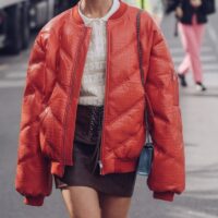 Devojka u mini suknji nosi kraću štepanu svetlo narandžastu jaknu