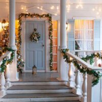 Ulaz u kuću dekorisan novogodišnjim ukrasima. Na vratima je prelep venac. Okićena su i vrata okolo, kao i gelenderi na prilazu vratima.