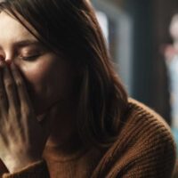 Žena, sklopljnih očiju, drži ruke preko lica sa izrazom patnje