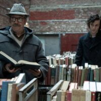 Dva glumca u filmu stoje u biblioteci.