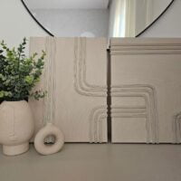 Slika napravljena od traka za prozor, bež je boje, a trakama je napravljena geometrijska šara i tekstura.