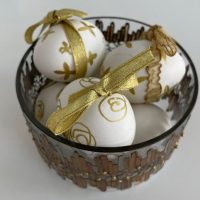 Bela jaja ukrašena ylatnim šarama i tračicama u dekorativnoj činiji spremna za uskršnju svečanost.