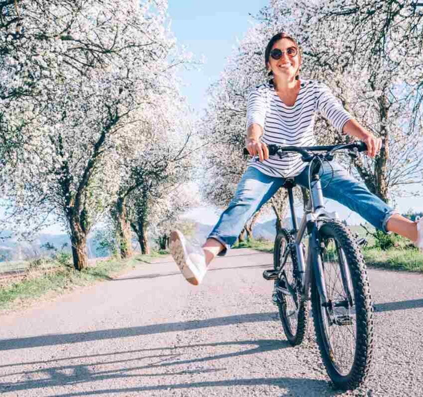 Nasmejana žena vozi bicikl.