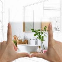 Ilustracija kako bi moglo da izgleda novo kupatilo. Prstima ruku je napravljen pokret kao da prikazuje sliku kako bi renovirano kupatilo moglo da izgleda.