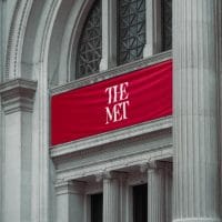 Ulaz u Metropoliten muzej u Nju Jorku, iznad ulaza je natpis met, belim slovima, na crvenoj tkanini.