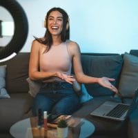 Influenserka u stanu snima selfie video. Instalirala je celu opremu, stalak za mobilni telefon, svetlo, lap top.