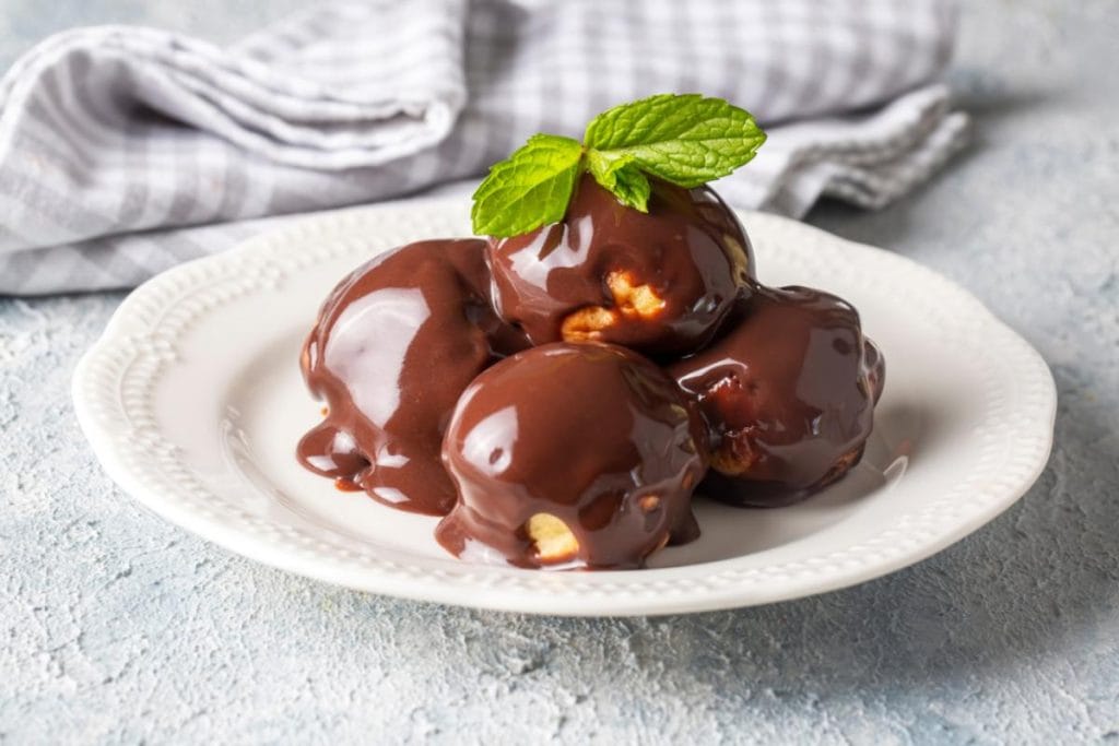 Profiterole prelivene čokoladom na tanjiru.