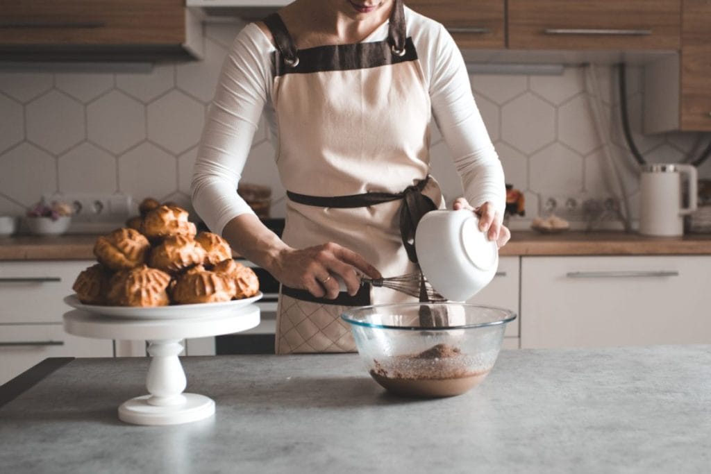 Žena u kuhinji priprema krem za profiterole.