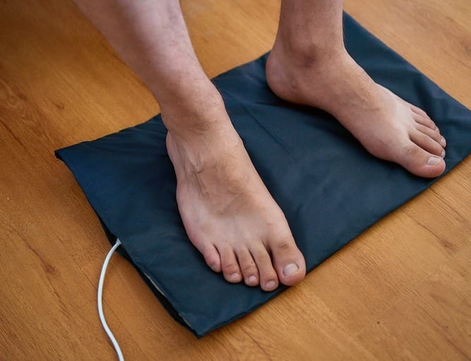 Podloga za uzemljenje, uključena u struju. Bosonogi čovek stoji na njoj.