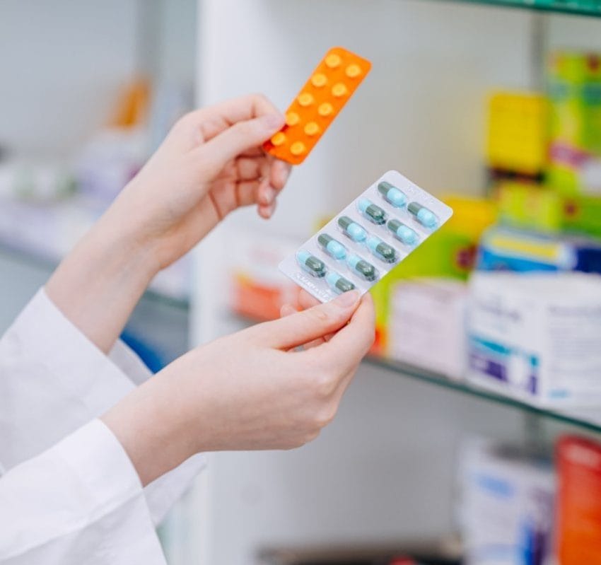 Farmaceut u apoteci u jednoj ruci drži suplement, a u drugoj lek.