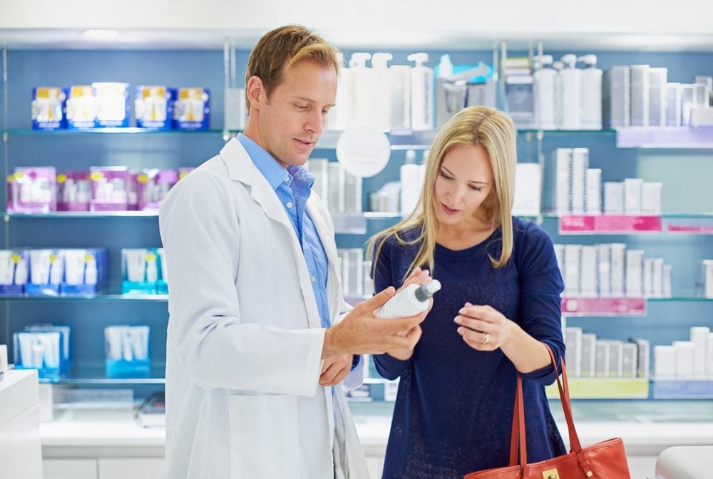 Farmaceut u apoteci daje savete ženi u vezi kreme.