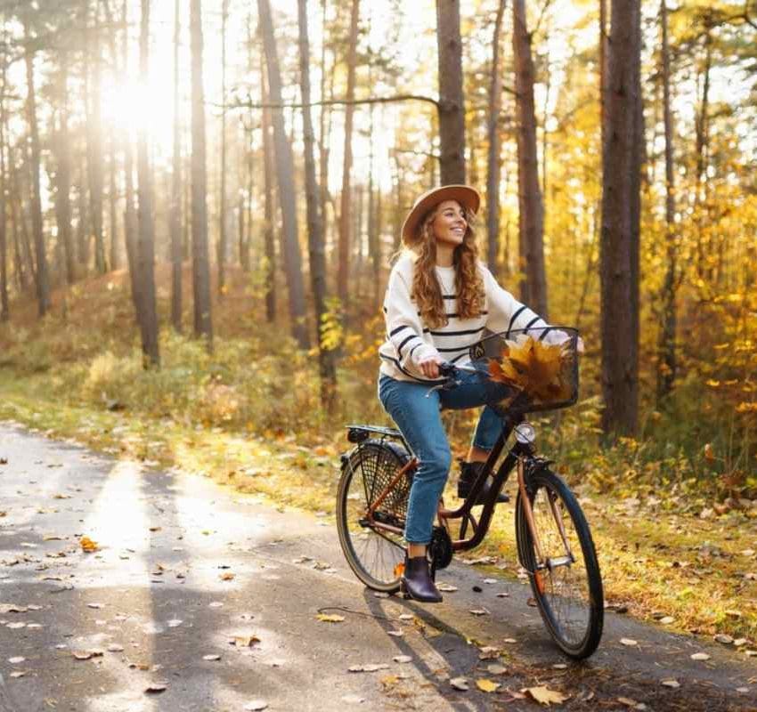 Jesenji period, drveće sa požutelim lišćem i žena koja vozi bickl.