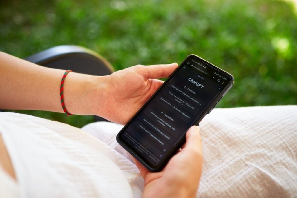 Devojka koja sedi u ruci drži mobilni vidi se da četuje sa chatgpt.