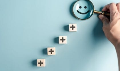 Kockice sa iscrtanim znakom plus, pore]anje jedna iznad druge, na vrhu je emoticon osmeh koji osoba posmatra kroz lupu.