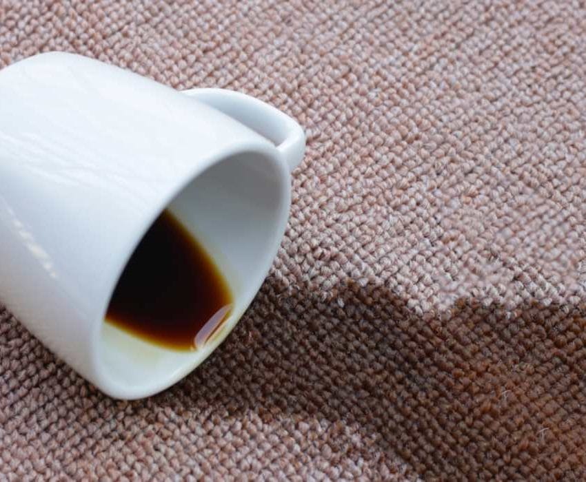 Šoljica iz koje prosuta kafa na bež tepih.