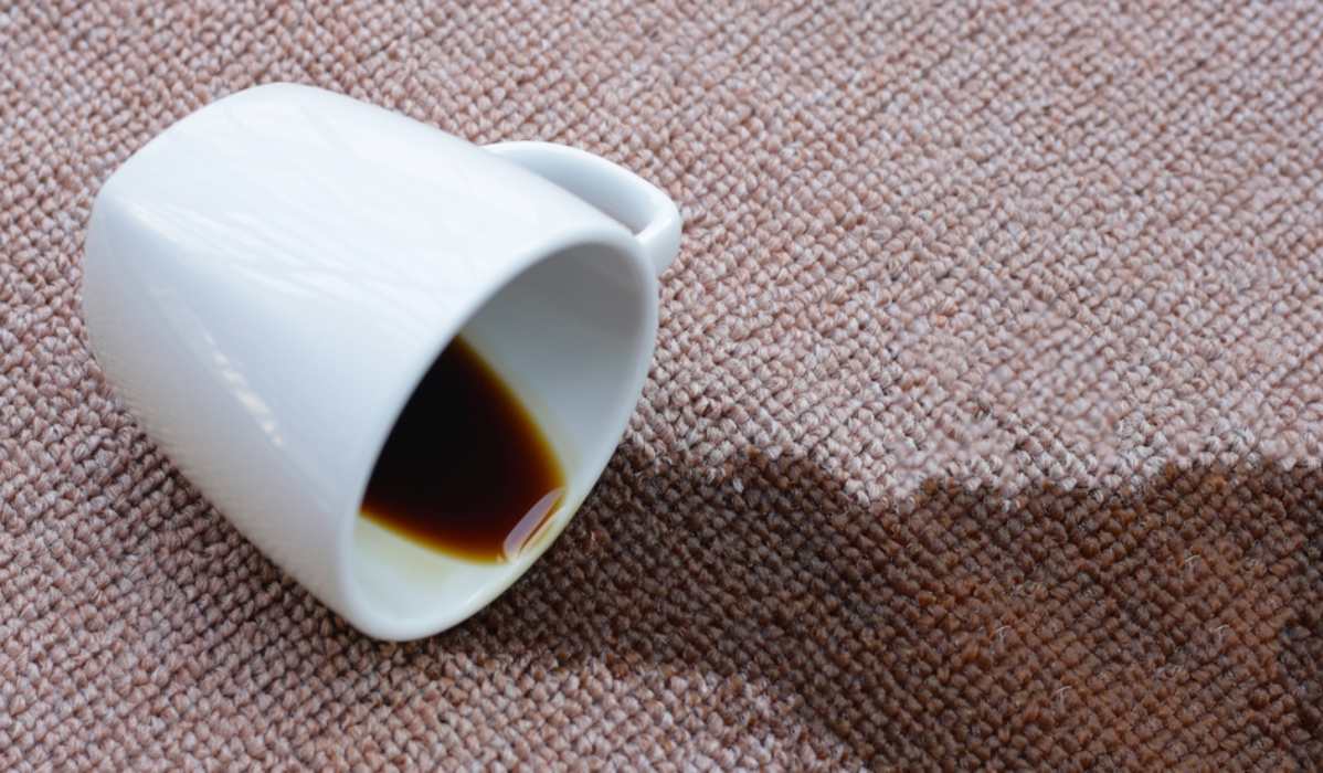 Šoljica iz koje prosuta kafa na bež tepih.