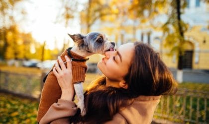 Žena u parku, jesenje boje, mazi se sa kucom, poljubac.