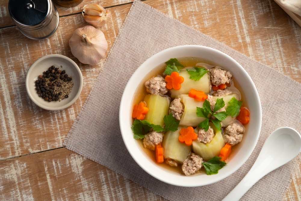 Čorbasto jelo od tikvica, šargarepe i mesa u činiji.