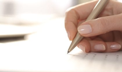 Vidi se ruka u kojoj je olovka. Nešto se ispisuje na papiru.