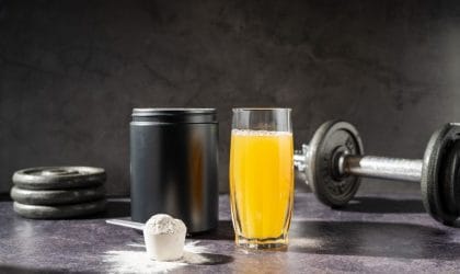 Izoleucin, suplement u prahu, pored je čaša sa sokom od pomorandže i tegići, sport.