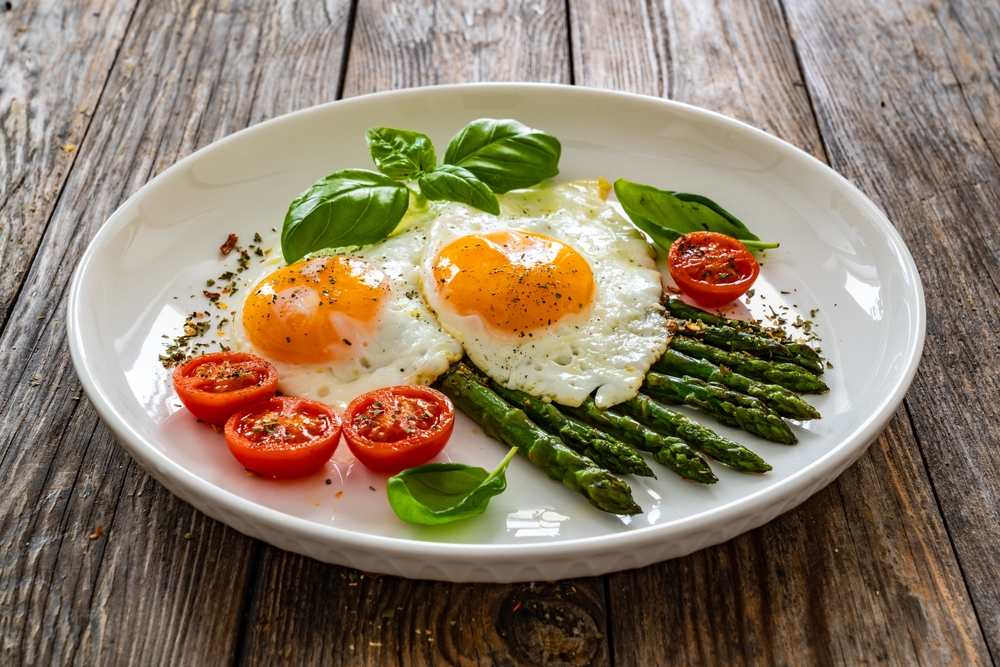 Jaja na oko. Na tanjiru su čeri paradajz i &scaron;pargla.