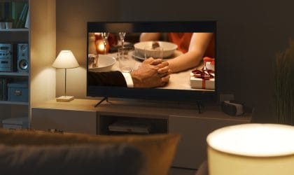 Dnevna soba, vidi se TV ekran, na kome je u prvom kadru muška ruka koja dodiruje žensku šaku.