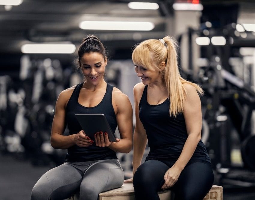 Žene u teretani gledaju u tablet.