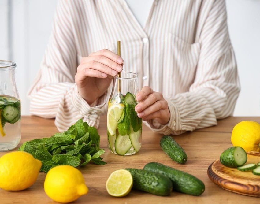 Žena priprema vodu za piće u bokal, stavlja limun, krrastavac, nanu.