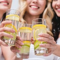 Tri žene nazdravljaju čašama sa vodom u kojoj su kolutovi limuna.