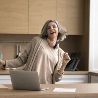 Žena u kuhinji sluša muziku i igra.