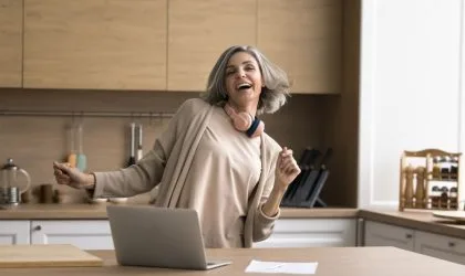 Žena u kuhinji sluša muziku i igra.