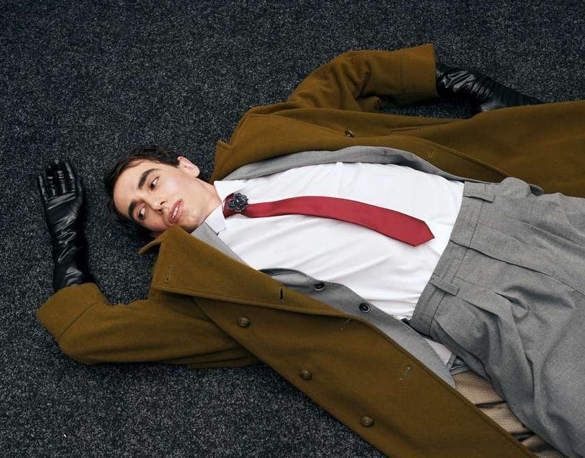 Mu[karac u svetlo braon kamilhar kaputu, leži.