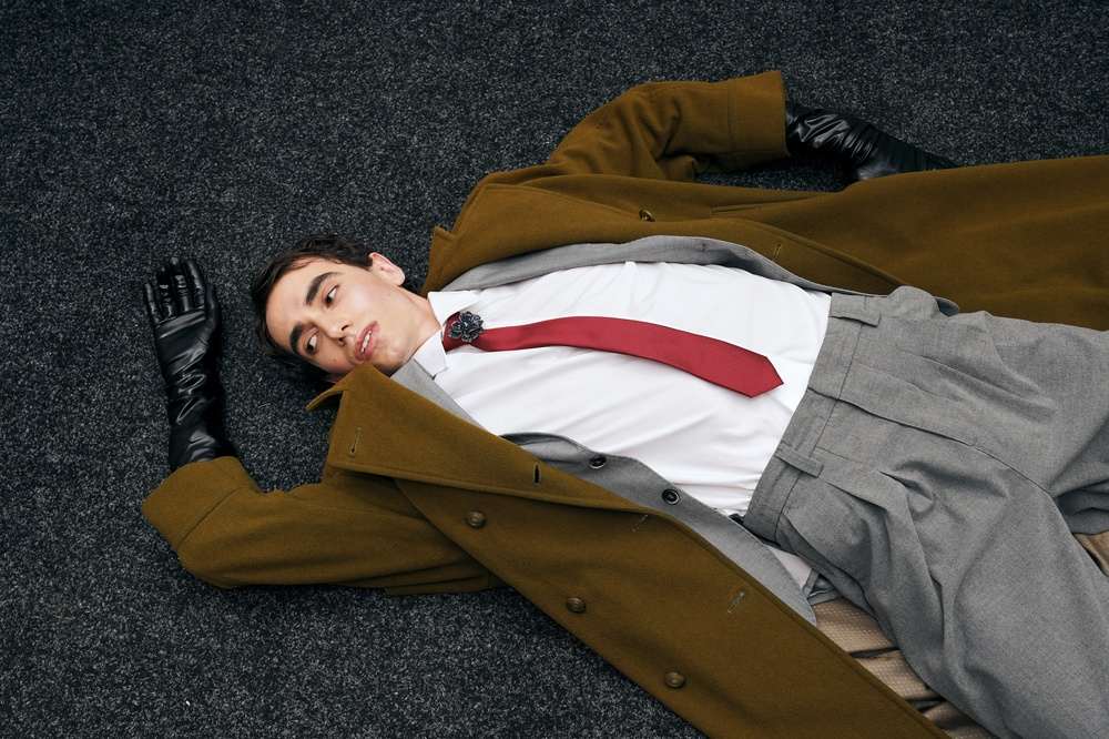 Mu[karac u svetlo braon kamilhar kaputu, leži.