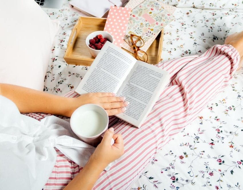 Žena ćita knjigu u krevetu.