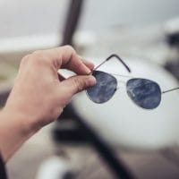 Pilotske naočare za sunce, drži ih muškarac u ruci.