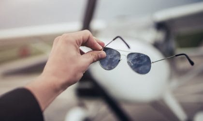 Pilotske naočare za sunce, drži ih muškarac u ruci.