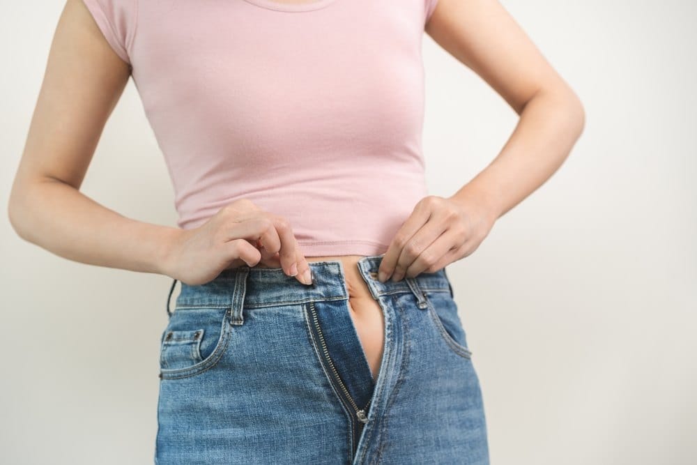 Žena koja je normalne građe ima problem da zakopča farmerke.